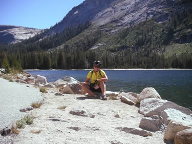 Jenn crouches by Tenaya Lake in Yosemite National Park.