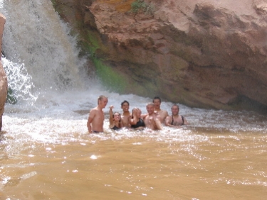 Dewey, Renee, Brian, Jessi, David, Will, and Phil have fun in the waterfall at Capital Reef National Park.