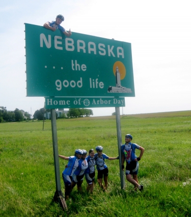 Peter Dewey, the self-proclaimed corn-husker, climbs up the sign all his excitement to enter Nebraska.